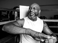 Black and white portrait of a Lululemon Ambassador smiling while wrapping boxing hands in a gym